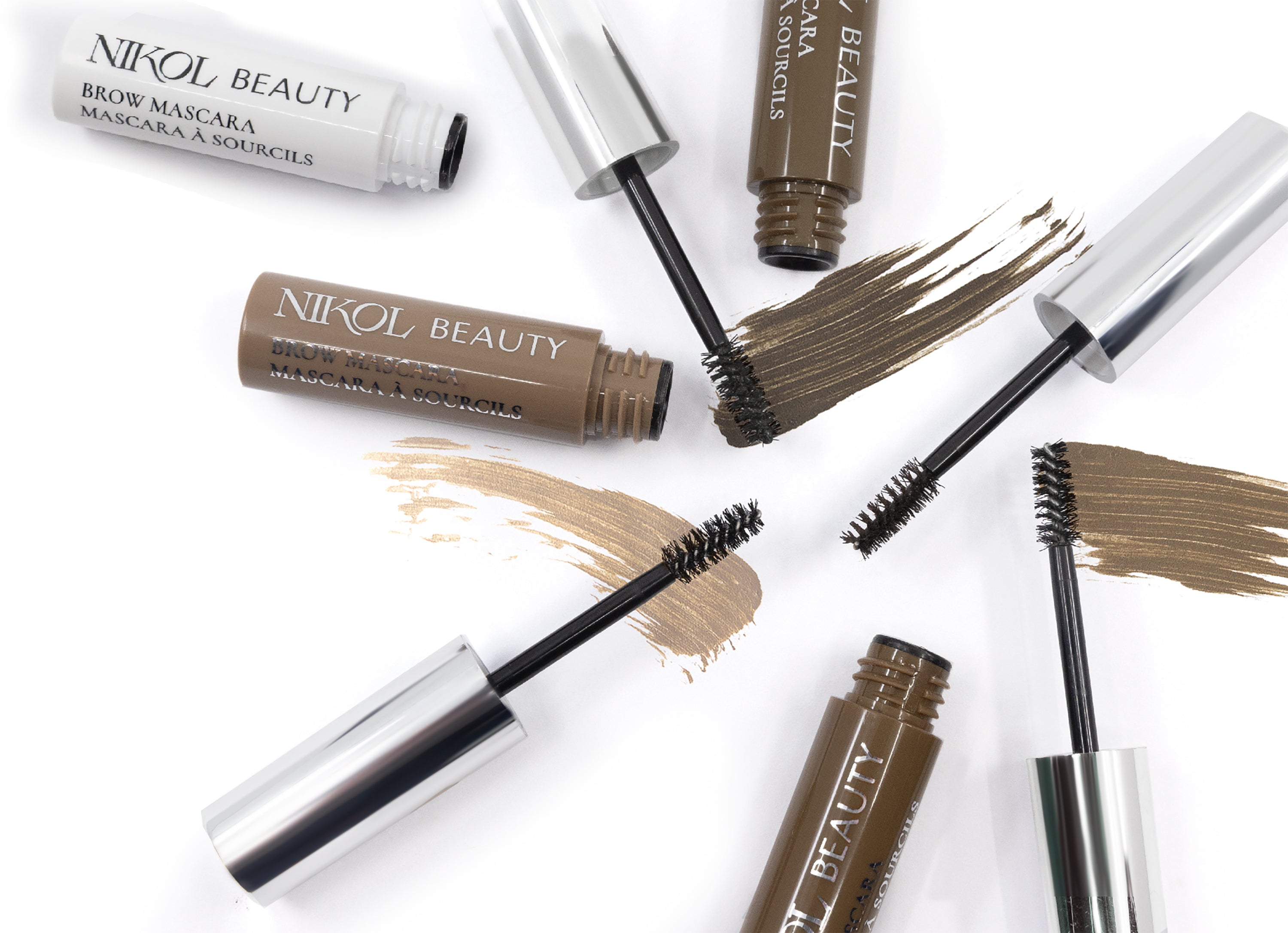 Shopgalaxys Brow Mascara tubes in various shades are open with wands displaying high-pigment browns. The wands lay on brush strokes of matching hues on a white background, promising defined eyebrows with each application.