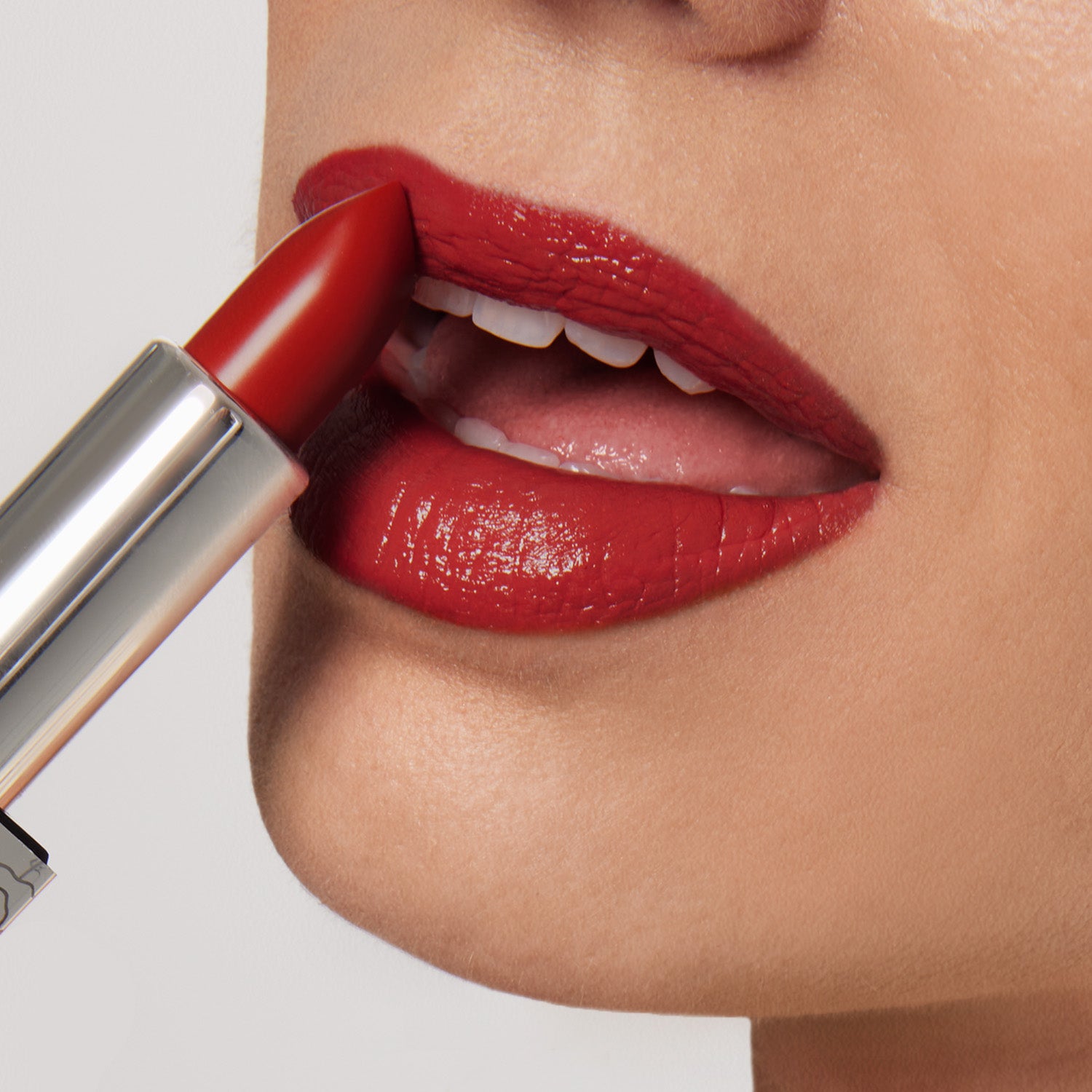 Close-up of someone applying Shopgalaxyss Confidence Shiny Velvet Cream Lipstick #173, a bright red with an ultra-creamy, hydrating formula. Only slightly parted, the mature lips reveal its rich color and glossy finish as the lipstick bullet angles toward the upper lip.