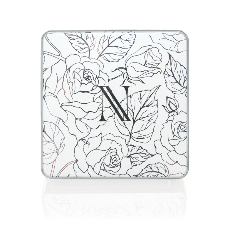 A square tin showcases an intricate floral line drawing, with a bold N at the center. The black-and-white design exudes classic elegance, mirroring the Sweet Carol 3-Well Eye Shadow Palette by Shopgalaxys, known for its vegan, clean beauty appeal.