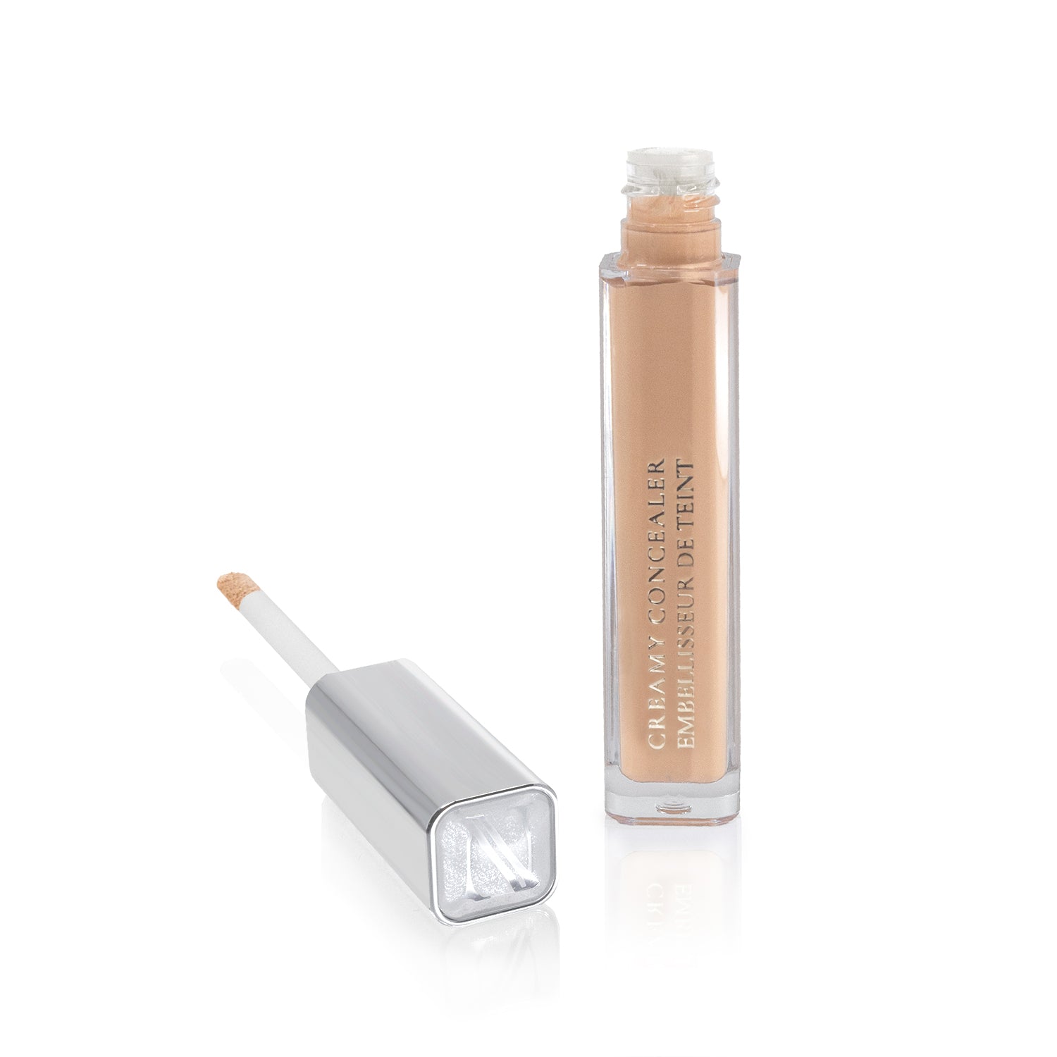 The rectangular, transparent tube of the Creamy Concealer from Shopgalaxys is open, revealing a beige creamy concealer inside. Beside it lies a silver cap with an applicator wand that shows high coverage concealer on its tip.