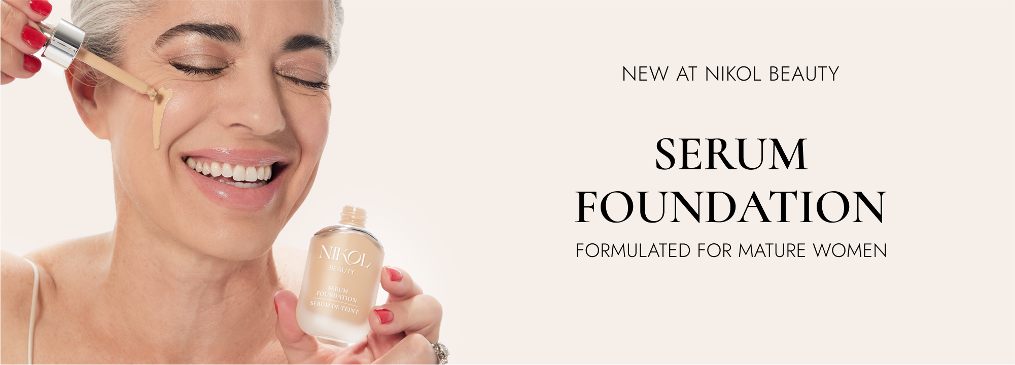 A smiling mature woman with gray hair applies liquid foundation to her cheek using a dropper, while holding a Shopgalaxys serum foundation bottle. Text reads: New at Shopgalaxys: Serum Foundation, formulated for mature women.