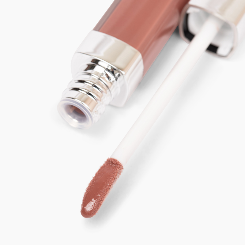 An open tube of Shopgalaxyss Good Vibes Lip Gloss #443 showcases a high-impact shine with a shiny silver cap and white wand. The rosy pink gloss promises comfortable wear, with the partially blurred tube resting on a white surface.